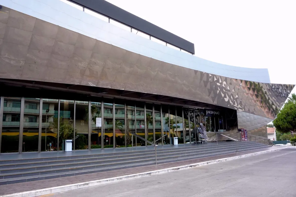 La fachada curva de acero espejado del Benidorm Palace sobre una amplia escalinata y las puertas de cristal de la entrada