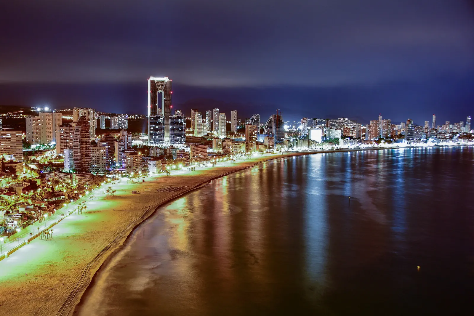 夜にライトアップされたベニドルムの海岸通りを上空から望む。砂浜の向こうにそびえる高い塔